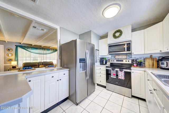 kitchen with a textured ceiling, light tile patterned floors, stainless steel appliances, decorative backsplash, and white cabinets