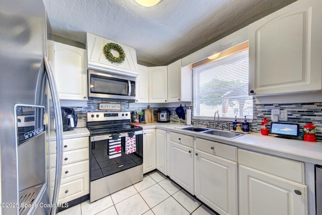 kitchen with appliances with stainless steel finishes, sink, white cabinets, backsplash, and a textured ceiling