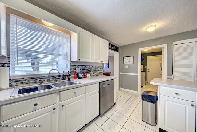 kitchen with tasteful backsplash, sink, white cabinets, stainless steel dishwasher, and a textured ceiling