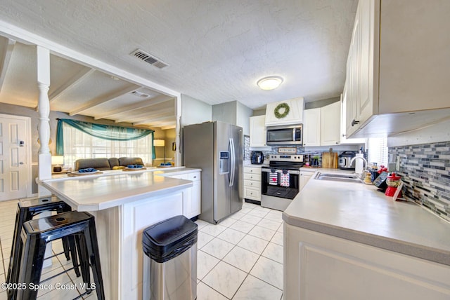 kitchen with appliances with stainless steel finishes, sink, white cabinets, a kitchen breakfast bar, and kitchen peninsula