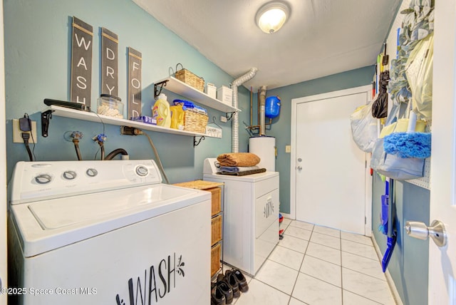 washroom with light tile patterned flooring, washing machine and dryer, and water heater