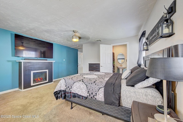 carpeted bedroom featuring ceiling fan, a tile fireplace, and a textured ceiling