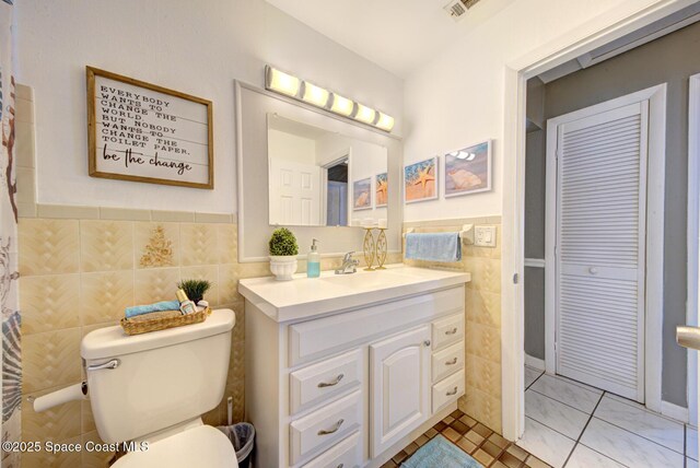 bathroom featuring tile patterned flooring, vanity, tile walls, and toilet