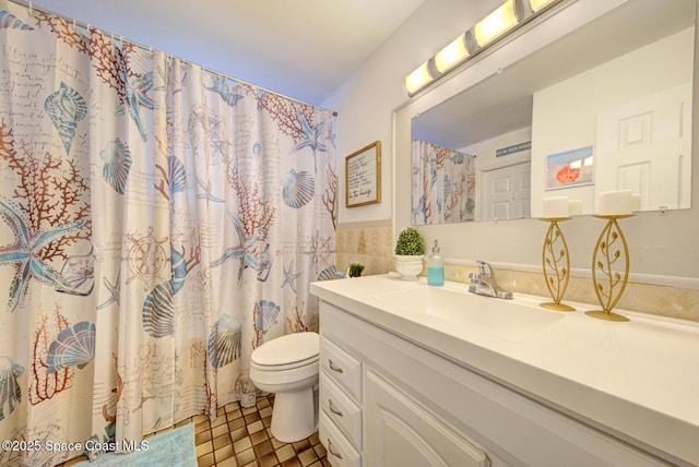 bathroom with tile patterned floors, toilet, tile walls, vanity, and curtained shower