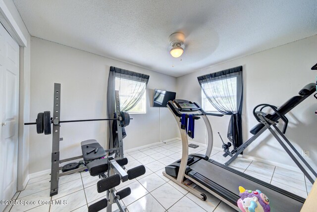 exercise room with light tile patterned flooring, ceiling fan, and a textured ceiling