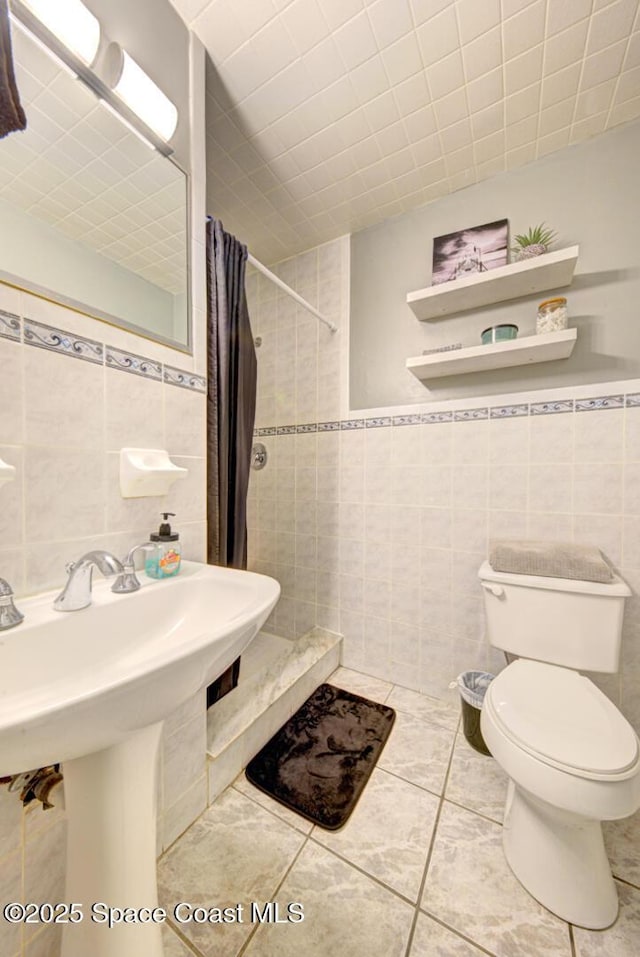 bathroom featuring sink, tile walls, tile patterned flooring, walk in shower, and toilet