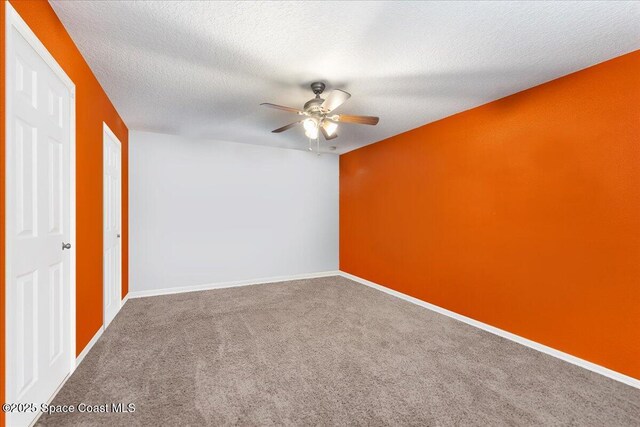 carpeted spare room with a ceiling fan, a textured ceiling, and baseboards