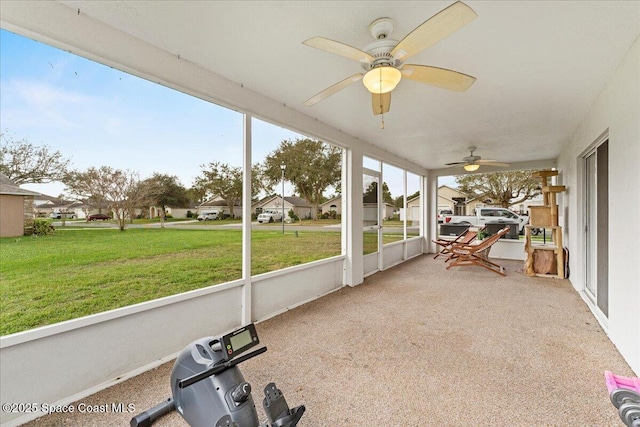 unfurnished sunroom with ceiling fan and a residential view