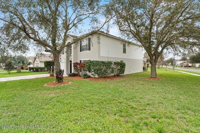 view of side of property with concrete driveway, a lawn, and stucco siding