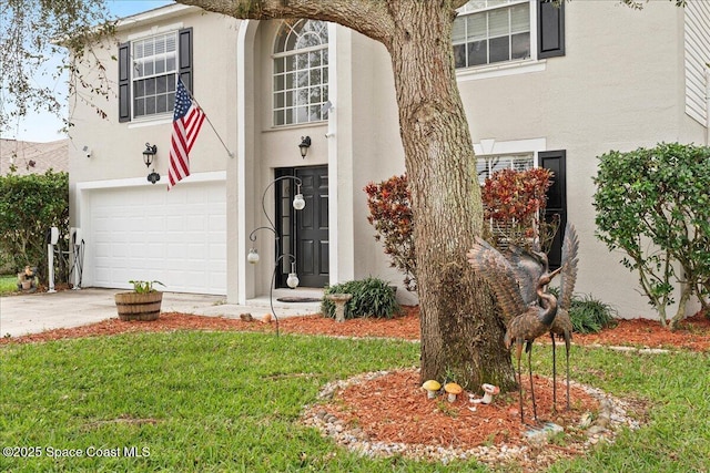 view of front of house featuring driveway, a front yard, a garage, and stucco siding