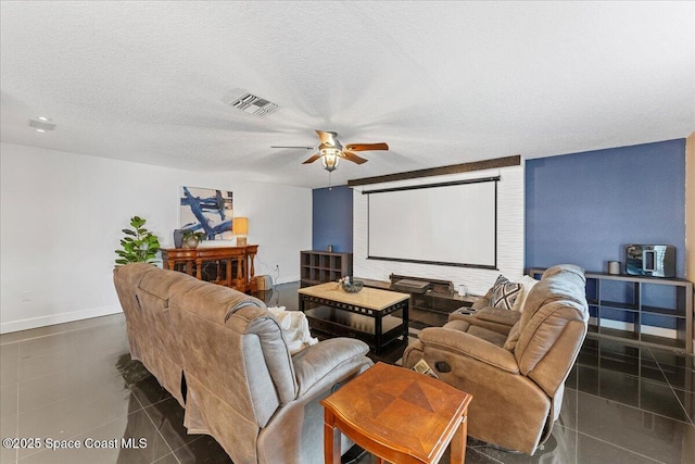 home theater room with visible vents, ceiling fan, a textured ceiling, dark tile patterned flooring, and baseboards