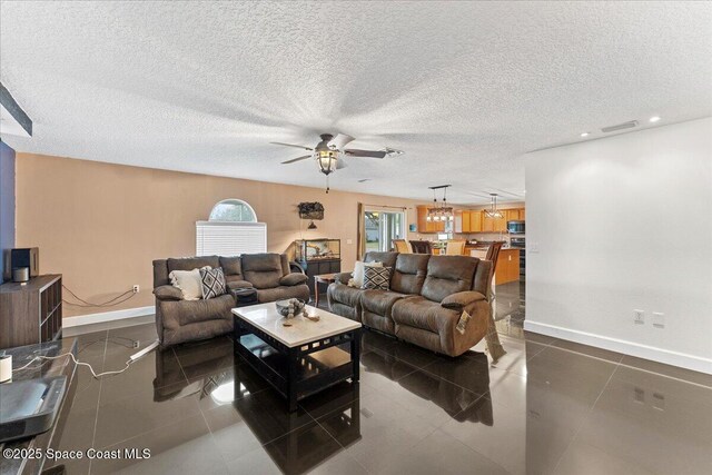 living room with dark tile patterned floors, baseboards, and a textured ceiling