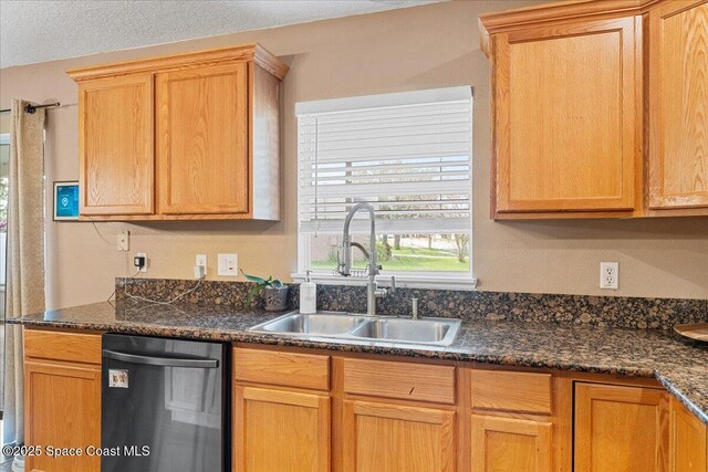 kitchen featuring dishwasher, dark stone countertops, and a sink