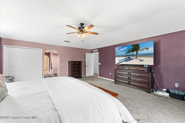 bedroom featuring a ceiling fan, arched walkways, visible vents, and carpet flooring