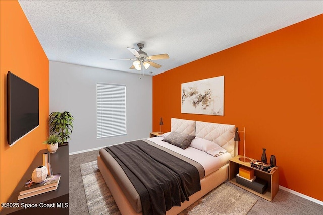 carpeted bedroom featuring a ceiling fan, baseboards, and a textured ceiling