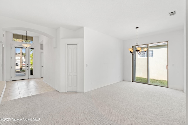 empty room with light carpet and a chandelier