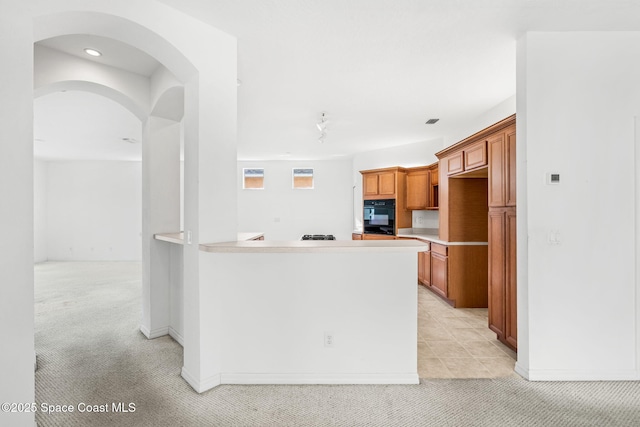 kitchen featuring light colored carpet, oven, and kitchen peninsula