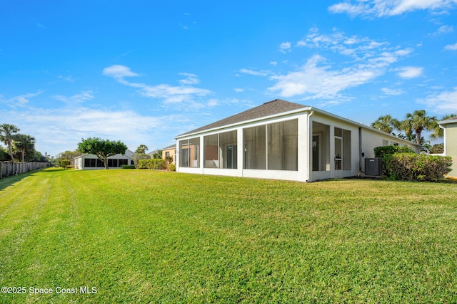 rear view of property featuring a sunroom, cooling unit, and a lawn