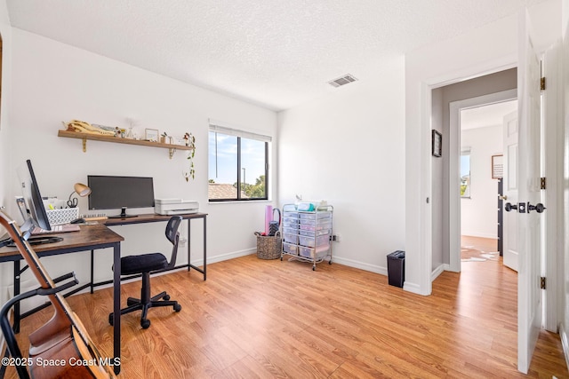 home office with a textured ceiling and light wood-type flooring