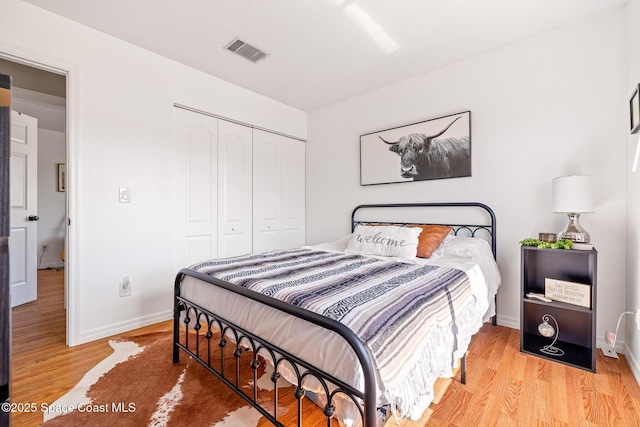 bedroom with light hardwood / wood-style floors and a closet