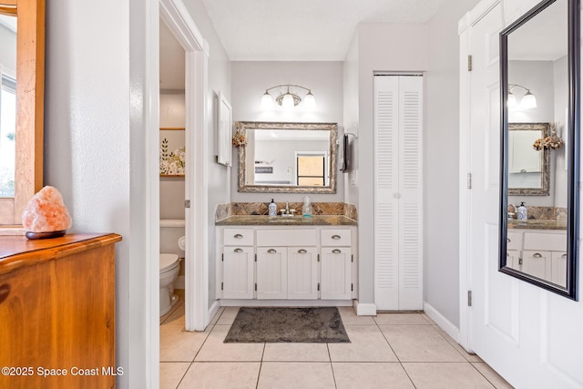 bathroom with vanity, toilet, tile patterned flooring, and a wealth of natural light