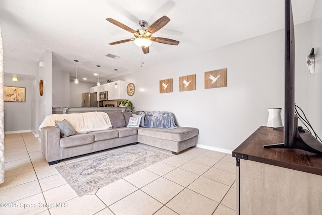 living room featuring a textured ceiling, ceiling fan, and light tile patterned flooring