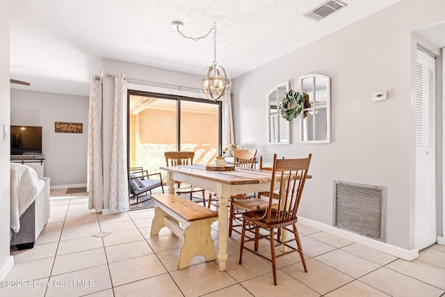 dining space with light tile patterned floors, a notable chandelier, and a textured ceiling