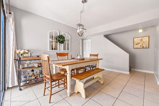 tiled dining area featuring a textured ceiling and a chandelier