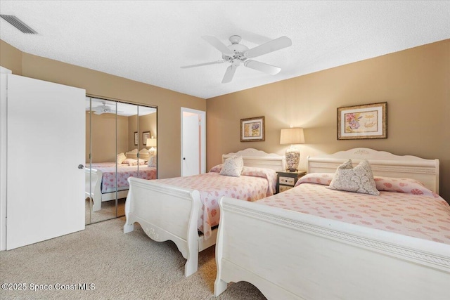 carpeted bedroom featuring ceiling fan, a closet, and a textured ceiling