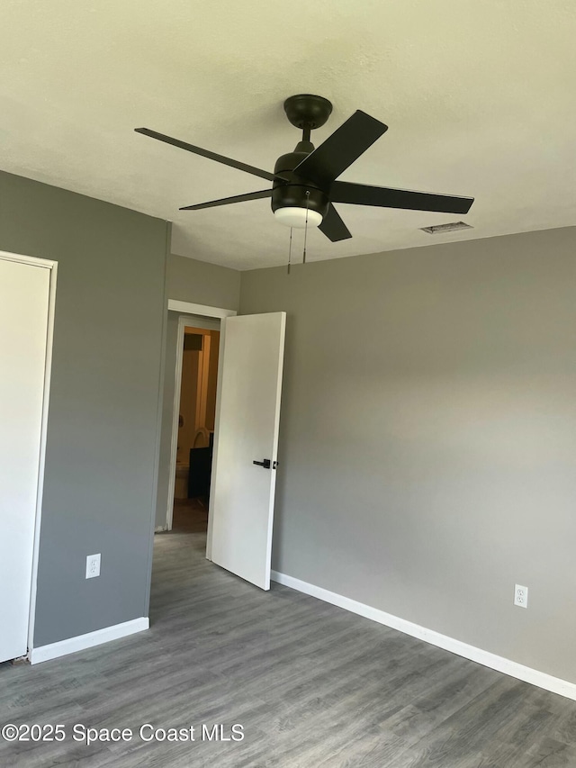 unfurnished room with a ceiling fan, dark wood finished floors, visible vents, and baseboards