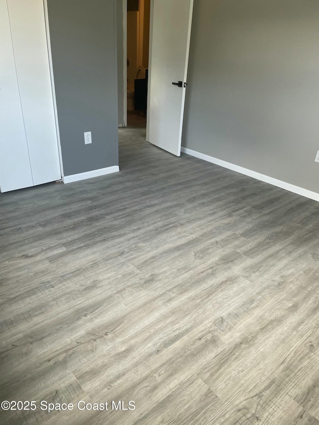 unfurnished bedroom with light wood-type flooring, baseboards, and a closet