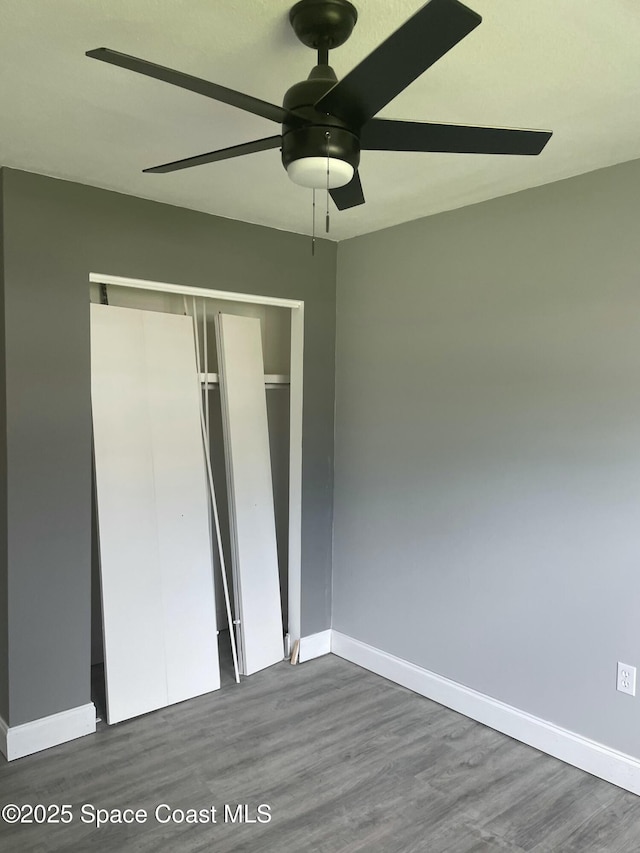 unfurnished bedroom featuring a closet, dark wood finished floors, and baseboards