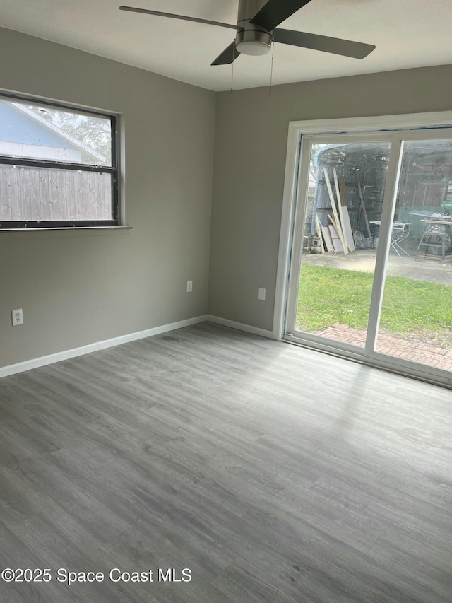 spare room featuring wood finished floors, a ceiling fan, and baseboards