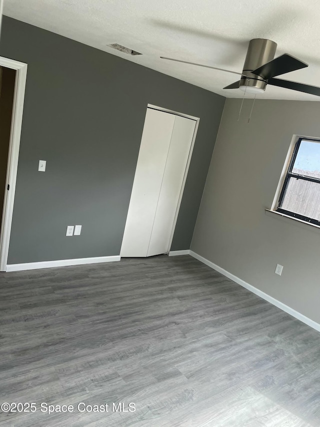 unfurnished bedroom with a textured ceiling, wood finished floors, visible vents, and baseboards