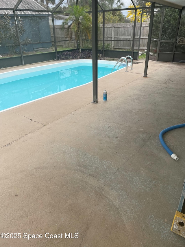 pool featuring glass enclosure, a patio area, and a fenced backyard