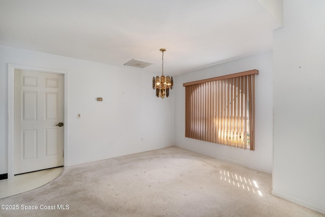 carpeted empty room featuring an inviting chandelier