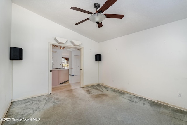 spare room with lofted ceiling, sink, light carpet, and ceiling fan