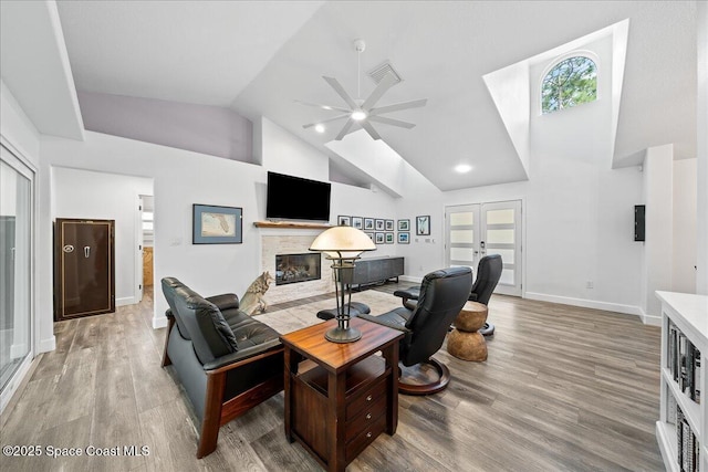 living room with ceiling fan, high vaulted ceiling, light hardwood / wood-style floors, and french doors