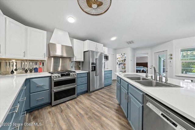 kitchen with white cabinetry, sink, stainless steel appliances, and wall chimney exhaust hood