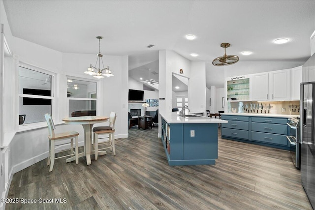 kitchen with lofted ceiling, blue cabinets, decorative light fixtures, dark hardwood / wood-style flooring, and white cabinets