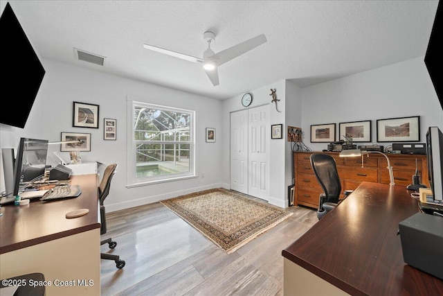 home office featuring light wood-type flooring, a textured ceiling, and ceiling fan