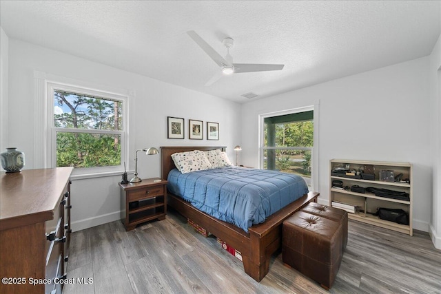 bedroom with ceiling fan, wood-type flooring, and a textured ceiling