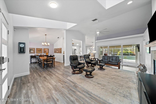 living room featuring high vaulted ceiling, ceiling fan with notable chandelier, and light wood-type flooring