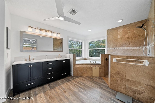 bathroom with a textured ceiling, vanity, independent shower and bath, hardwood / wood-style flooring, and ceiling fan