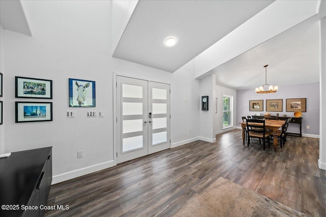 entryway with french doors, lofted ceiling, dark hardwood / wood-style floors, and a notable chandelier