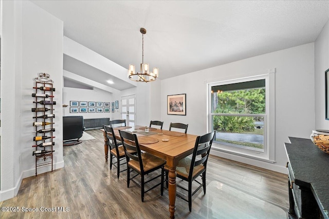 dining area with lofted ceiling, hardwood / wood-style flooring, and a chandelier