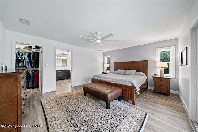 bedroom with a spacious closet, a textured ceiling, and light wood-type flooring