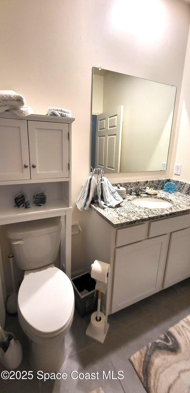 bathroom featuring tile patterned floors, vanity, and toilet