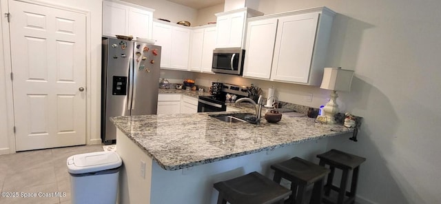 kitchen with stainless steel appliances, white cabinetry, a breakfast bar area, and kitchen peninsula