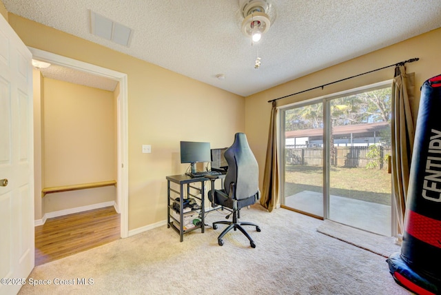 carpeted home office featuring a textured ceiling